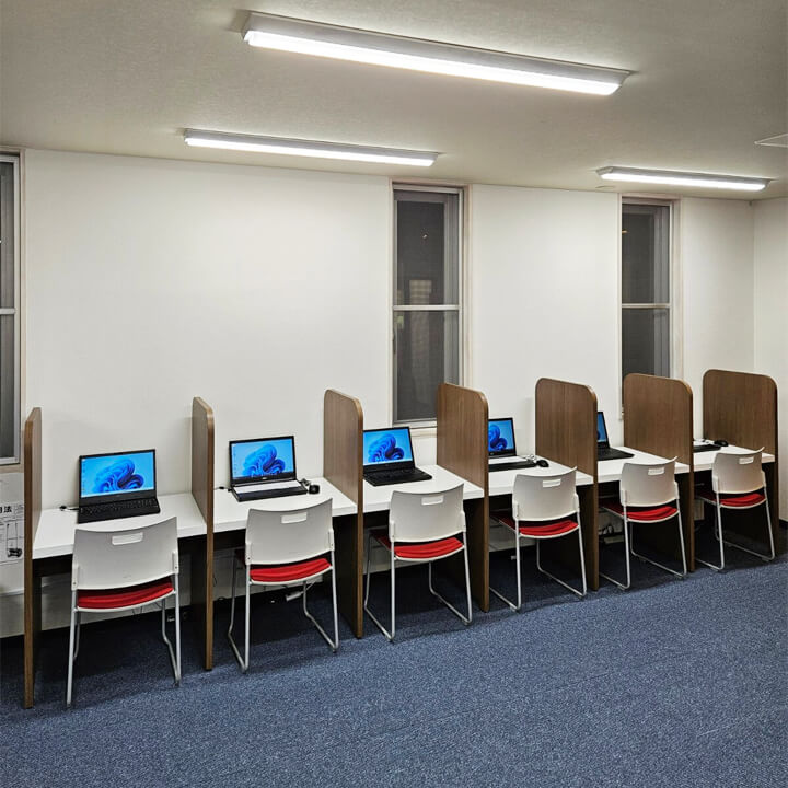 個別に間仕切りが付いていてパソコンが置かれた机がいくつも設置されている訓練スペースの様子